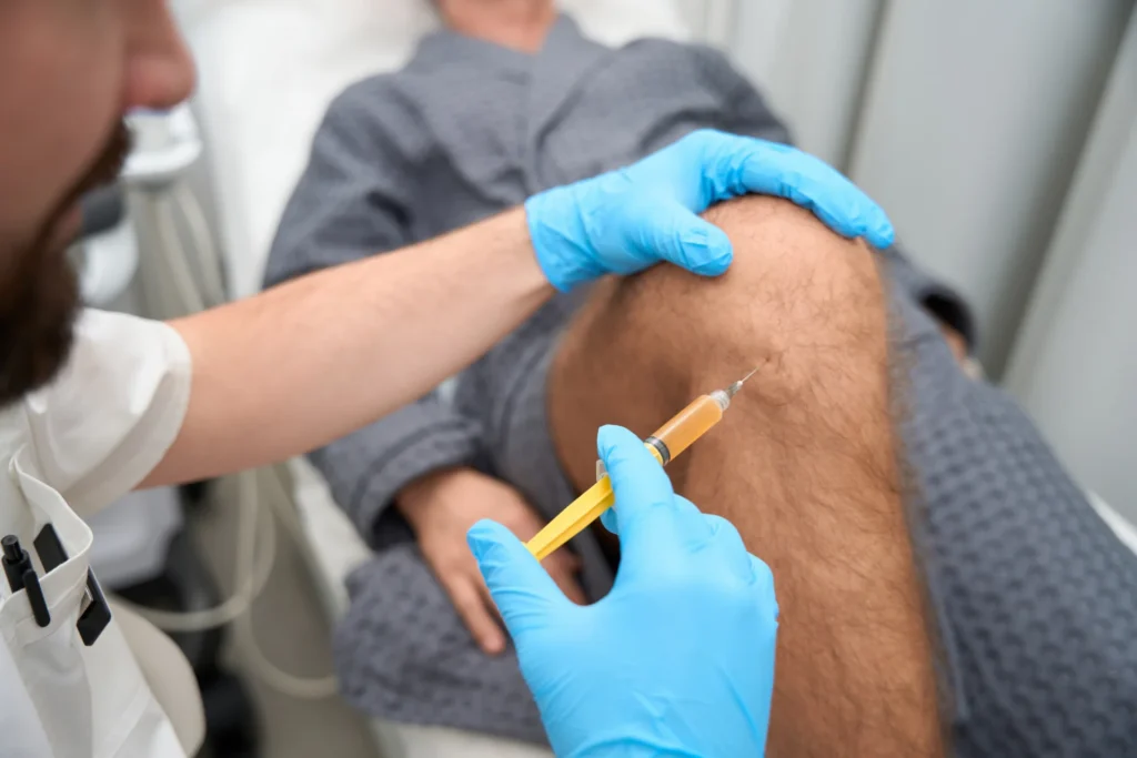 doctor injecting knee of patient with yellow