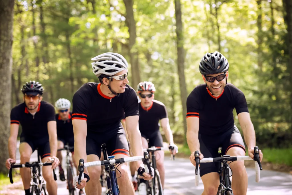 group of men cycling together on a forest road
