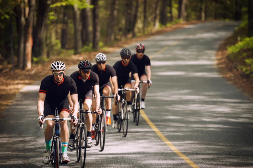 group of men cycling together on a winding forest