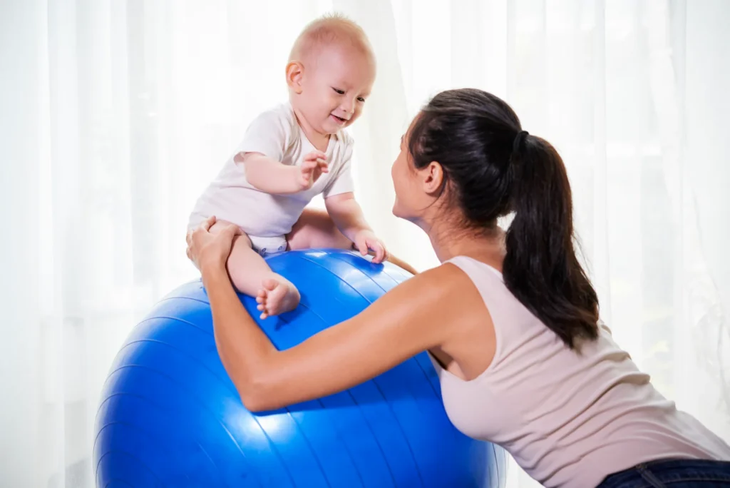 smiling baby with woman on fitness ball