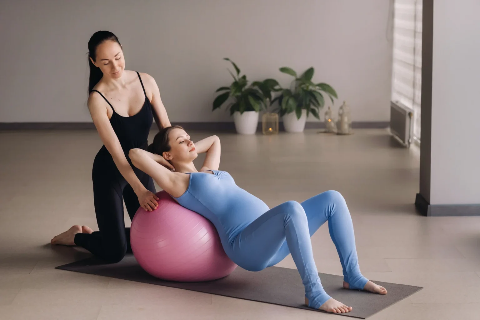 woman exercises with fitness ball with instructor